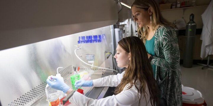 Student working with chemicals under a hood with an instructor