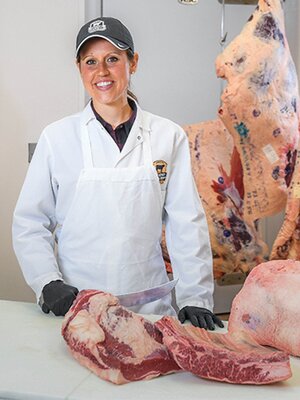 Portrait of Diana Clark cutting meat